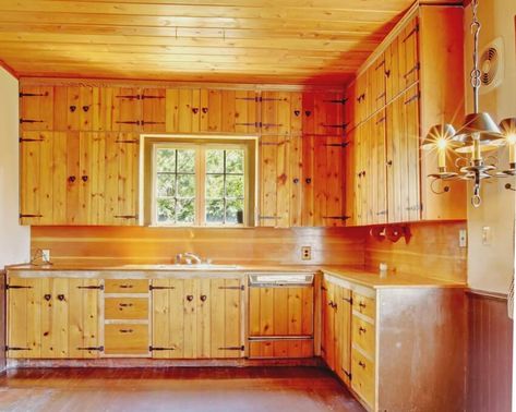 An old kitchen interior with wooden floors, knotty pine kitchen cabinets and ceiling Pine Cabinet Doors, Update Pine Kitchen Cabinets, Knotty Pine Kitchen Ideas, Tongue And Groove Kitchen Cabinets, Natural Pine Kitchen Cabinets, Countertops With Pine Cabinets, Knotty Pine Cabinets Makeover, Pine Walls Kitchen, Wood Ceilings Kitchen