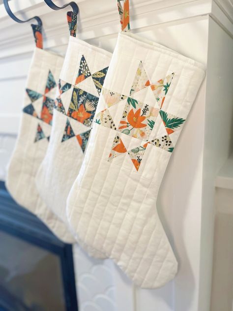 This is a handmade quilted stocking made with Rifle Paper Company fabric. The fabric details the flower of a red-orange poinsettia flower, with green leaves, gold dots and flower stems, and a cream-white background. The main stocking color is a cream-white. Natal, Patchwork, Quilted Stockings Christmas, Quilted Christmas Stockings Ideas, Patchwork Stocking, Small Quilted Gifts, Quilt Stocking, Christmas Stocking Pattern Free, Quilted Stocking