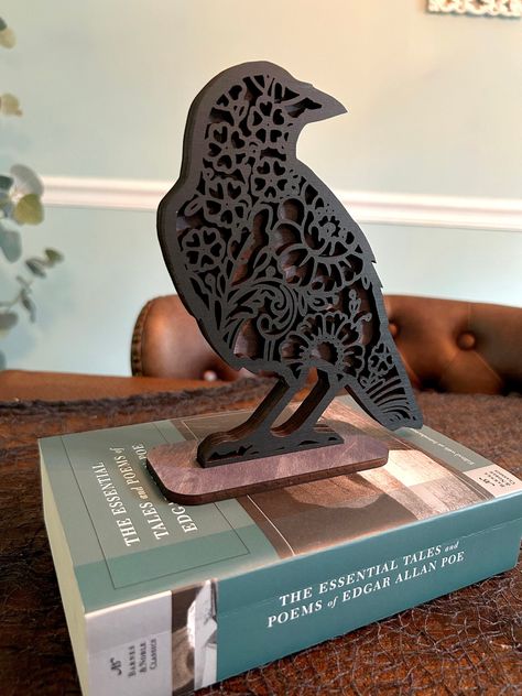 This beautiful and spooky raven decoration is intricately designed and laser cut out of maple plywood. The top lace layer is painted black and mounted over a gray stained bottom layer. Contains a wooden stand for 3-d display. Makes a perfect Halloween decoration! Unique Laser Cut Ideas, Diy Wood Halloween Decor, Halloween Laser Cut Ideas, Halloween Laser Projects, Laser Cut Projects Ideas, Laser Cut Gift Ideas, Wooden Shelf Decor, Laser Cut Halloween, Diy Laser Engraver