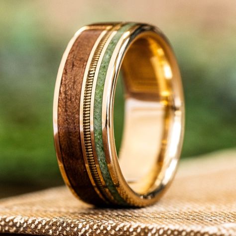 Introducing "The Wayfarer" - a bespoke gold wedding band handcrafted by our skilled artisans in North Carolina, embodying the spirit of exploration and adventure. Inlaid with guitar string, vibrant green imperial diopside and 1903 Springfield rifle stock wood. These materials forged together create a distinctively unique and rustic look.The Wayfarer Gold Ring Features:  SCS certified 100% recycled gold ring base An offset guitar string inlay (your choice) Green imperial diopside offset ring inla Non Metal Wedding Rings For Men, Gold Men Rings Wedding, Men's Gold Jewelry, Tungsten Mens Rings Wedding, Classic Mens Wedding Bands, Manly Bands, Tungsten Rings For Men, Mens Unique Wedding Rings, Spinning Wedding Ring