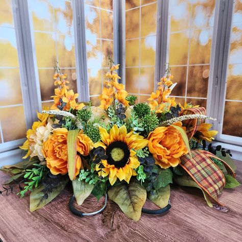 Newly added to the shop!! This headstone hugger is a beautiful way to honor and remember your loved one during the fall and Thanksgiving season. Bright sunflowers and peonies accented plaid bows. Who doesn't love a good traditional plaid for the holidays? Take advantage of the sale going on right now in the shop for this and all other seasonal decor. #headstoneflowers #gravesiteflowers #cemeteryflowers #sunflowerarrangement #memorialflowers #honorlovedones #cemeteryarrangements #vabbd #... Fall Headstone Saddles, Sunflowers And Peonies, Fall Cemetery, Headstones Decorations, Gravesite Decorations, Flowers Sunflowers, Fall Centerpieces, Sunflower Arrangements, E Flowers