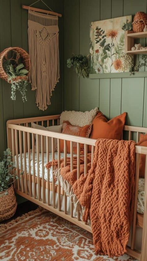 Green nursery with rust-colored accents, featuring macramé wall hanging, earthy textures, and cozy knit blankets. Neutral Colour Nursery Ideas, Nursery With Light Wood Crib, Fall Theme Nursery, Wooded Theme Nursery, Nursery Light Green Walls, Cactus Nursery Ideas, Boho Nursery Colors, Peaceful Nursery Ideas, Green And Peach Nursery