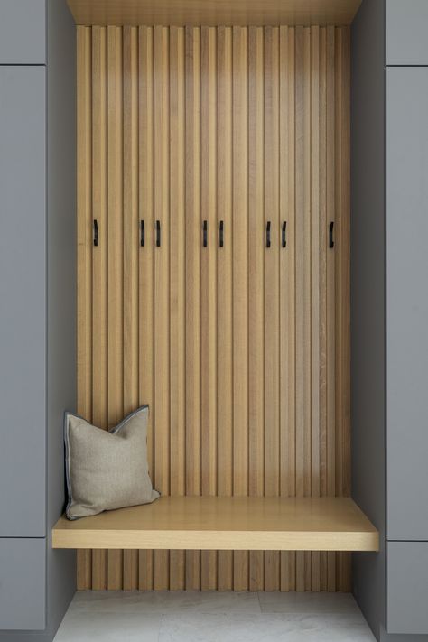 In the capacious mudroom, the soft white walls are paired with slatted white oak, gray nanotech veneered lockers, and a white oak bench that blend together to create a space too beautiful to be called a mudroom. There is a secondary coat closet room allowing for plenty of storage for your 4-season needs. Modern Mudroom Bench With Storage, Slat Wall With Bench, Slat Wall Mudroom, Entry Niche, Contemporary Mudroom, White Oak Bench, Mudroom Hooks, Mudroom Entry, Shed Roof Design