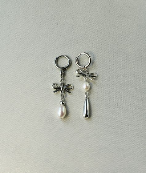 These mismatched earrings feature grade AAA fresh water pearls and the cutest bow charms, bringing a touch of romanticism into your everyday. They're the perfect piece for a coquette and feminine look. These earrings are hypoallergenic, as well as lead and nickel-free. For optimal care, be sure to keep away from moisture! Inner hoop diameter: 10 mm Tip: all my earrings come in pairs, meaning that "1 quantity" equals one pair. ;) Bow Hoop Earring, Earings Aesthetics, Mismatched Earrings Ideas, Dangly Silver Earrings, Coquette Earrings, Mismatch Earrings, Homemade Earrings, Romantic Earrings, Cute Coquette