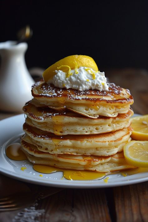 Stack of pancakes topped with whipped cream, lemon slices, and syrup on a white plate. Ricotta Pancakes Recipe, Ricotta Lemon Pancakes, Lemon Ricotta Pancakes With Bisquick, Gluten Free Lemon Ricotta Pancakes, Lemon Ricotta Pancakes Recipe, Gourmet Pancakes, Fluffy Lemon Ricotta Pancakes, Lemon Ricotta Pancakes With Blueberry Syrup, Lemon Pancakes