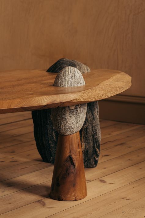 A new body of work from Oliver brings his skilled carving and deft combination of wood over stone into a pair of functional low tables. In each table, a Scottish timber surface is held in place over three rocks, pierced and anchored by gravity alone. There is heft and lightness, ritual and romance at play here. They echo standing stone circles and early altars. Oliver says: “The three rocks in each table are Lewisian gneiss, one of the oldest geological forms in Britain. It dates back to around 3000 million years, and was formed in the creation of mountains. There is a visual and physical balance to these tables; all parts are held in place by natural forces.” “Whilst building Table 01, I felt an instinctive response to keep the Elm slab whole with its natural edge intact. With Table 02 I Log Wood Table, Rock Furniture, Nature Furniture, Tree Stump Side Table, Stone Circles, Wood Slab Table, Custom Wood Furniture, Stone And Wood, Furniture Design Inspiration