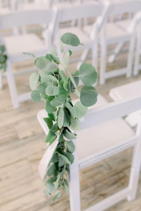 Beautiful and simple ceremony chair decor made from eucalyptus greenery and white ribbons. This is the white and bright ceremony space at 48 Fields, an authentic dairy barn venue in Virginia's Loudoun County.  #militarywedding #weddingceremony #weddingdecor #virginiawedding #barnwedding #countrywedding #farmwedding Eucalyptus Wedding Chairs, White Chair Decor, Wedding Chair Greenery, Eucalyptus Chair Decor, Simple Beach Wedding Ceremony Decor, Eucalyptus Aisle Decor, Simple Ceremony Decor Outdoor, Eucalyptus Wedding Aisle, Wedding Ceremony Chair Decorations