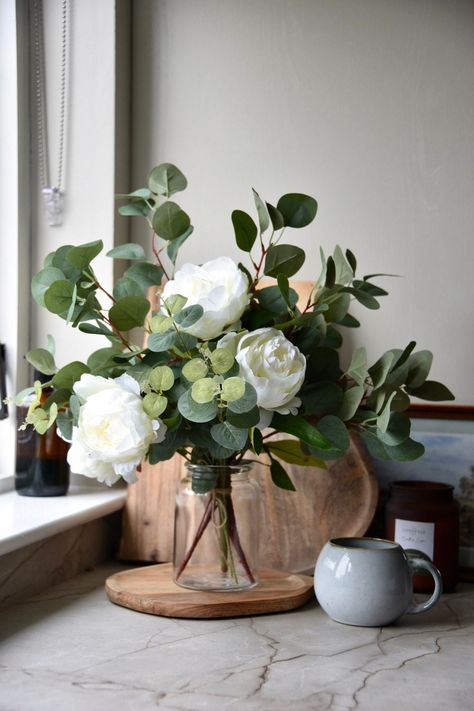 This beautiful ivory floral arrangement is very realistic.  It includes large peony roses and eucalyptus It is internally wired so that it can be bent to retain the desired shape.  Beautiful paired with a simple vase. This faux flower arrangement is timeless and made to fit into any home, whether it be a farmhouse, modern decor or simplistic.  An alternative use is wedding centre pieces or decor as they are elegant and timeless. All flower arrangements are handmade in Northern Ireland.  Options: Flower Arrangement With Eucalyptus, Peony And Eucalyptus Centerpiece, Flowers In Kitchen Decor, Simple Faux Flower Arrangements, Peony Floral Arrangements Wedding, Wedding Peonies Decoration, Sage Green Flower Arrangements, Large Faux Flower Arrangements, Flower House Decor