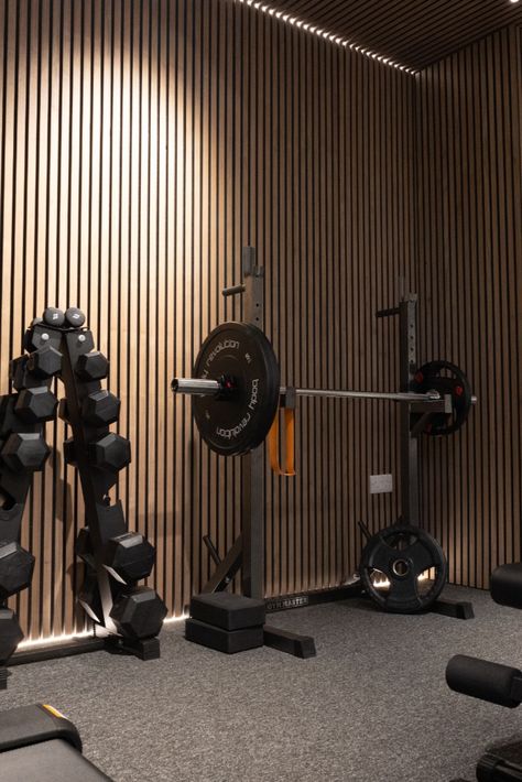 The home gym has been fitted with this acoustic wood panel on the wall and ceiling. This adding a wonderful detailed effect that creates interest and patterns when the light hits. Garage Fitness Room, Garage Wall Paneling Ideas, Gym Lighting Ideas Ceilings, Gym Feature Wall, Studio Gym Design, Gym Wall Ideas, Basement Gym And Family Room, Gym Ceiling, Basement Rental