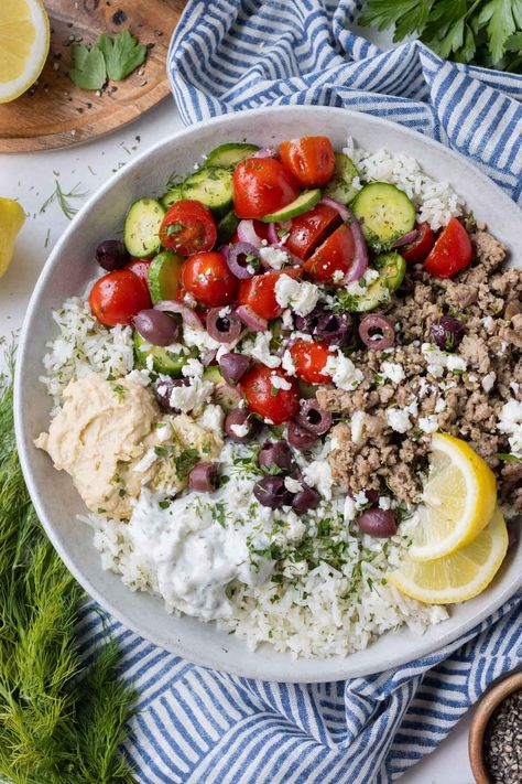 These Greek Ground Turkey Rice Bowls are bursting with fresh Mediterranean flavor from a homemade Greek seasoning mix—the secret to why the ground turkey tastes so incredible! Paired with bright lemon and herb rice, a cucumber tomato salad, and a duo of tzatziki sauce and hummus, they are one of our go-to meal prep options on busy weeknights—even picky eaters give this one two thumbs up! Greek Hummus Bowl, Greek Ground Chicken Bowls, Ground Turkey Recipes For Dinner Mediterranean, Turkey Greek Bowl, Greek Turkey Rice Bowl, Greek Bowls Ground Turkey, Mediterranean Turkey Bowl, Ground Turkey Mediterranean Bowl, Ground Turkey Tzatziki Bowls