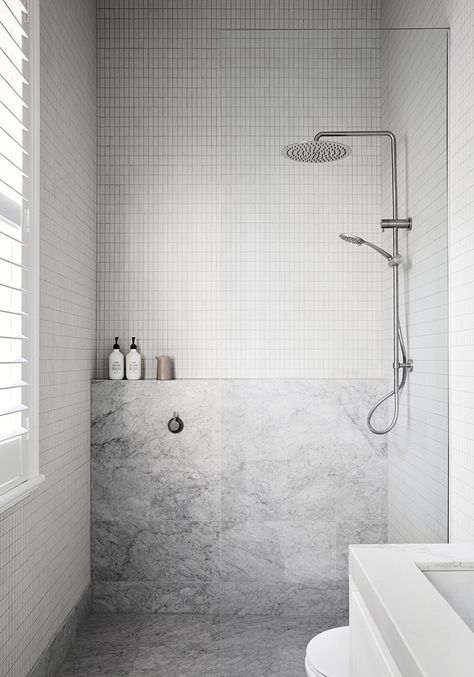 This all-white interior heritage cottage renovation is a dream! Empire Interiors creates depth and interest in this all-white home using stone, brick, moulding and playing with neutral colours. This modern minimalist bathroom is a small a glimpse into this beautiful heritage renovation. Bathroom styling: white subway tiles, grey hald wall design, nickel tapware, simple shampoo and conditioner bottles, window shutters. Check out the full tour of this timeless Edwardian house by clicking the pin! Makeover Kamar Mandi, Tropical Inspiration, Tiled Bathroom, Shower Toilet, Albert Park, Cottage Renovation, Interior Minimalista, Sopot, St Kilda