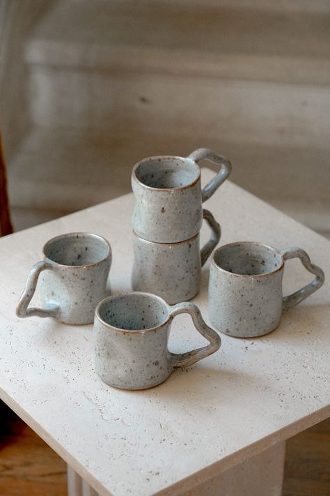 This handcrafted wavy ceramic mug features a unique minimalist design with a smooth, flowing handle and our signature crackled glaze in a cloud grey-blue color. Made from stoneware, it's perfect for your daily tea or coffee, adding a modern touch to any kitchen. Each mug is carefully crafted, making it a thoughtful gift for pottery lovers. Dimensions: Height 3.5" x Width 3.5" All items are dishwasher safe, but highly recommend handwashing with care to preserve their craftsmanship. Since each pie Pottery Cup Design, Coffee Shop Mugs, Unique Mug Design, Pottery Mug Handles, Ceramic Mug Handles, Handmade Mugs Pottery, Mug Handles, Ceramic Minimalist, To Go Coffee Cups