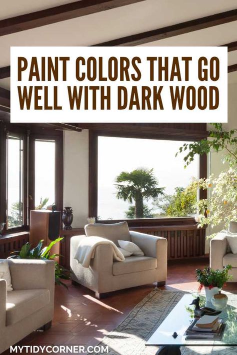 Love dark wood but unsure about paint colors? Discover the top paint colors that go with dark wood trim, floors, cabinets, furniture, paneling, etc. Here are the best paint colors that go well with dark wood. Enhance your decor with the best paint colors that pair with dark wood! Create a harmonious look with these paint colors that pair well with dark wood. Living Room Dark Trim Light Walls, Living Room Paint Color Ideas Dark Floor, Dark Wood Window Trim With Blinds, What Paint Color Goes With Dark Wood Trim, Dark Trim Interior Paint Colors, Paint Color For Dark Wood Trim, Paint That Compliments Dark Wood, Paint Colors That Compliment Dark Wood Floors, Walnut Floors Living Room Paint Colors