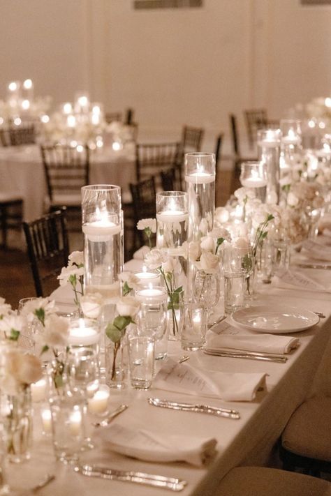 A stunning reception setup featuring delicate white florals and glowing candlelight, creating an atmosphere of romance and sophistication. Perfect for a timeless wedding celebration. #CandlelitWedding #ElegantReception #WhiteFlorals #RomanticAmbiance #WeddingInspiration White And Candle Wedding, Candle Decor For Weddings, Small Indoor Reception, Reception Set Up, Classy Indoor Wedding, Wedding Table With Candles, Candle Wedding Table Decor, Candle Tablescapes Wedding, Indoor Wedding Reception Decorations