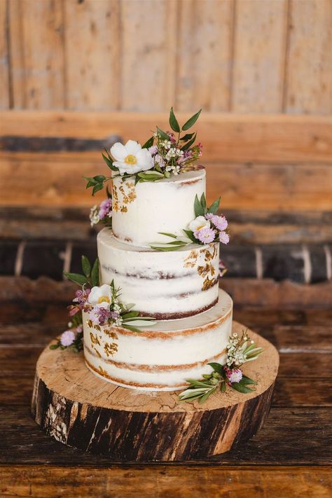 Rustic semi naked wedding cake with flowers and buttercream on a log slice cake stand www.samandlouise.co.uk Rustic Cake Flowers, Rustic Tiered Cake, Log Cake Stand Wedding, Rustic Carrot Cake Wedding, Rustic Flower Wedding Cake, Crumb Wedding Cake, Distressed Wedding Cake, Wedding Cake On Log Slice, Wedding Cake Natural Flowers