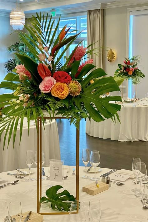 Tall Tropical Centerpiece on gold stand Tropical Arrangements Centerpieces, Hawaiian Flower Centerpieces, Diy Tropical Centerpieces Wedding, Floor Centerpieces, Tropical Foliage Arrangements, Wedding Palm Leaves, Modern Tropical Wedding Centerpieces, Palm Frond Decor Wedding, Tropical Arrangements Floral Design