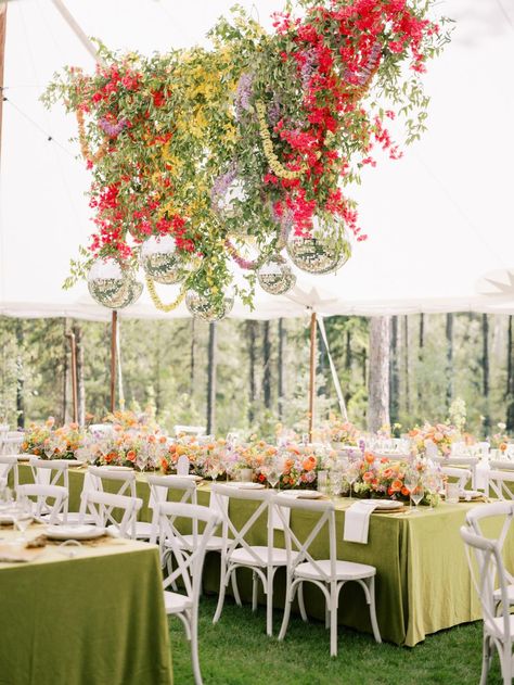 This stunning reception setup features vibrant florals cascading from above, paired with disco balls for a fun and glamorous touch. The mix of colors and greenery creates a joyful, lively atmosphere. For more show-stopping décor ideas, visit Style Me Pretty! 🌸✨  Photography: Jeremiah and Rachel Photography (http://www.jeremiahandrachel.com) Disco Ball And Greenery Ceiling, Colorful Arrangements, Vibrant Florals, Pretty Photography, Secret Garden Wedding, Bar Set Up, Disco Balls, Wedding Coordinator, Bar Design