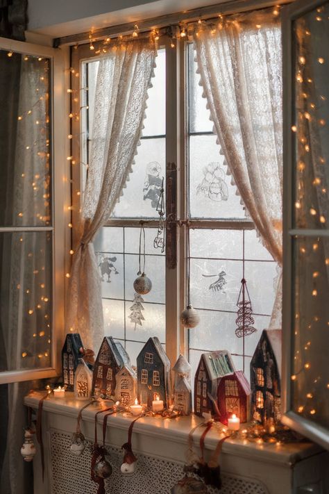 A cozy indoor window decorated with vintage Christmas houses, fairy lights, and lace curtains, creating a nostalgic holiday atmosphere. Indoor Window Christmas Decor Ideas, Window Christmas Decor Ideas, Window Christmas Decor, Nostalgic Christmas Decorations, Vintage Christmas Decor Ideas, Window Christmas, Holiday Window Display, Vintage Christmas Lights, Christmas Dreaming