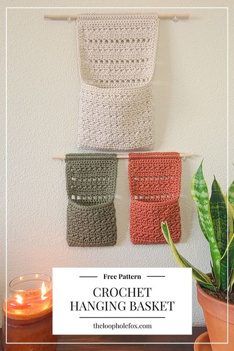 Perfect for those who like to keep things organized and have something pretty and fun to look at, The Millie Crochet Hanging Basket checks off all boxes. This pattern combines a crochet wall hanging with a pouch-like crochet basket to free up your desk or other surfaces by hanging on the wall. Crochet Projects Basket, Hanging Storage Crochet Pattern, Crochet Hanging Pattern, Crochet Book Organizer, Crochet Housewarming Gift Ideas, Crochet Room Storage, Crochet Ideas For Home Decor Inspiration, Crochet Hanging Hammock, Crochet Book Hanging