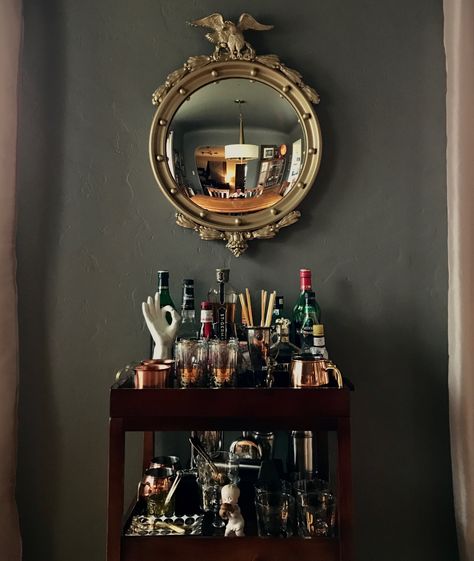 Moody Bar Cart, Bar Cart Wall Mirror, Two Living Room Ideas, Decanter Display Bar Cart, Bar With Antique Mirror, Dark Academia Bar Cart, Classy Bar Cart, Goth Bar Cart, Vintage Bar Cart Styling