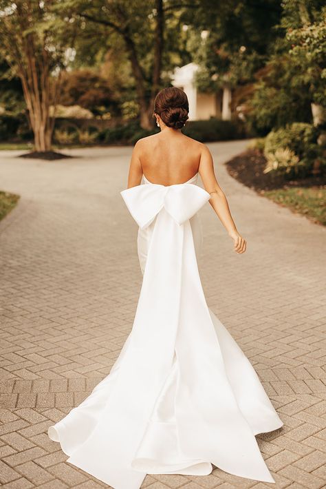 Classic and Elegant Summer Bride Style with a Full Neat Bridal Updo and Low Back Mermaid Fit Gown with Large Pressed Bow Statement Bow Wedding Dress, Silk Mermaid Wedding Dress Satin, Slick White Wedding Dress, Bow Wedding Dress Low Back, White Satin Wedding Gown, Ballgown Style Wedding Dresses, Dramatic Sleeves Wedding Dress, White Wedding Dress With Bow, Wedding Dresses Silk Long Sleeve