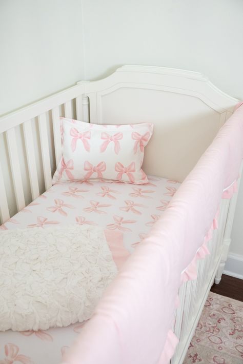 Estimated to start shipping Sept. 19. The Bows 6-pc. Crib Bedding Set features an eye-catching petal pink bow pattern. The perfect petal pink bow set for any nursery. Includes: Petal pink crib rail cover, straight, with petal pink linen ruffled trim, monogram optional Petal Pink Bows Crib Sheet, soft bamboo fabric Petal Pink Linen Crib Skirt, Gathered, deck top and split corners, 16" drop. Cream Herringbone Blanket Petal Pink Bows Baby Pillow Sham Baby Sham Pillow Insert Optional: Finish your nu Pretty In Pink Nursery, Pink Stripe Nursery, Baby Crib Pillow, Eloise Themed Nursery, Cute Girl Nursery Ideas, Pink French Nursery, Pottery Barn Girls Nursery, Love Shack Fancy Baby Nursery, Baby Girl Pink Bow Nursery