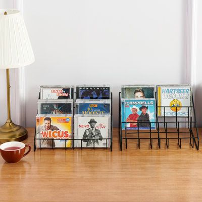 Get ready to organize your CD collection in style with this set of 2 tabletop CD jewel case organizers. Featuring a modern matte black metal wire frame, each organizer boasts three tiers of shelving and six compartments to keep your CDs neatly organized. With a capacity of approximately 36 jewel cases per standing holder and a total capacity of 72 CD cases, these organizers are perfect for use at home, in a retail setting, or in any other location where you want to display your collection. CDs a Organisation, Album Display Ideas, Cd Collection Display, Cd Organizer, Dungeon Decor, Cd Organization, Cd Display, Cd Shelves, Cd Jewel Case