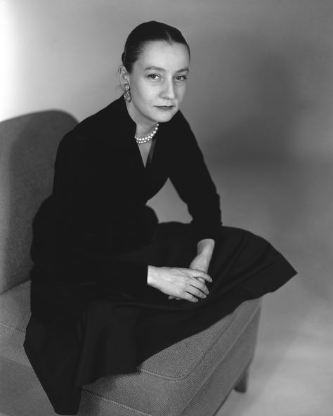 “Conde Nast fashion editor, Babs Simpson, aka Mrs. William Simpson, seated cross-legged on a chair, wearing a dark long sleeved top and dark skirt, a two strand set of pearls, a pair of earrings and her hair in a tight chignon.” Monochromatic Photography, Vogue Photography, Dark Skirts, Betty Ford, Work Women, Cross Legged, Vintage Fashion 1950s, Gibson Girl, Conde Nast