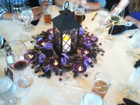 Lantern and purple centerpieces Purple And Black Table Centerpieces, Black And Purple Wedding Centerpieces, Blue And Purple Gothic Wedding, Black And Purple Centerpieces, Black And Purple Wedding Theme Wedding Table Decor, Purple And Black Wedding Theme, Black And Purple Wedding Theme, Royalcore Wedding, Purple And Black Wedding