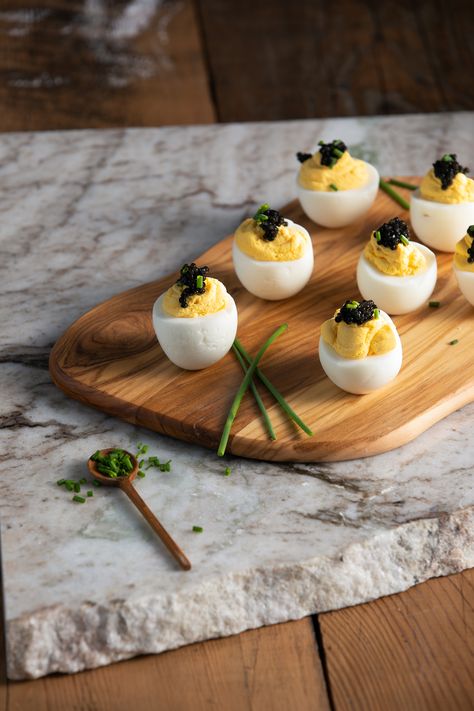 a wooden board on a piece of white and gray marble on a wooden table with six deviled eggs topped with caviar and garnished with chives Caviar Recipes, Deviled Eggs, Flavor Profiles, To Shine, Appetizer, A Team