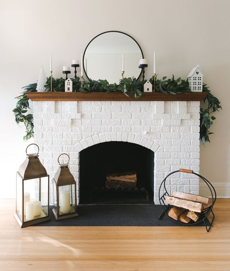 Holiday fireplace mantel, black and gold candle holders, white trees, and lanterns. Fireplace Lantern, Holiday Mantel Decor, Scandinavian Holidays, Lanterns Fireplace, Holiday Mantel, Holiday Table Decorations, Timeless Decor, Holiday Sparkle, Fireplace Mantel