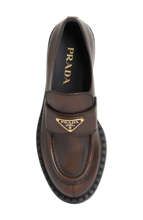 The Prada emblem marks the band of this classic moc-toe loafer lifted on a thick rubber sole and crafted from chocolatey burnished leather. 1 3/4" (50mm) heel Leather upper and lining/rubber sole Designer Shoes Brown Prada Loafers, Womens Loafers Outfit, Prada Loafers Women Outfit, Ysl Loafers, Loafers For Women Outfit, Prada Loafers, Classy Shoes, Loafer Women, Prada Shoes