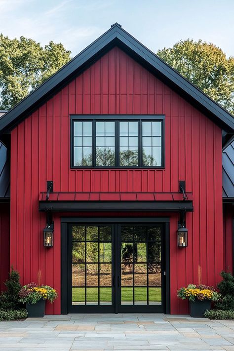 Modern barn style red house facade with black barn doors in a green farmhouse. Check out all of these creative and charming barn-style houses, blending rustic charm with modern functionality. These will change they way you look at barns completely. Red And Black Barndominium, Barn Homes Interiors, Barn Turned Into House, Barn Exterior Colors, Barn Colors Scheme Exterior, Barn Window Ideas, Black Barn Doors, Old Barn Restoration, Barn Exterior Ideas