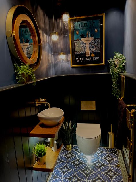 Downstairs cloakroom with wall hung toilet and sink. Victorian style floor sets off the lower tongue and groove boarding painted in F&B Railings and the upper wall and ceiling painted in F&B Stiffkey Blue. Brushed gold flush plate, taps and accessories add to the glamorous feel. Warm oak floating shelves, plants,  and a vintage style poster in a gold frame soften the look. A cascading chandelier, low power spot lights and lighting under the loo and sink shelves provide plenty of warm light Industrial Bathroom Ideas, Small Downstairs Toilet, Bathroom Ideas On A Budget, Eclectic Bathroom, Downstairs Toilet, Industrial Bathroom, Small Bathroom Ideas On A Budget, Small Bathroom Ideas Modern, Bathroom Design Inspiration