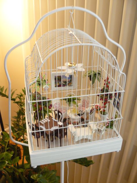 Patty's porch in a bird cage ~ My customer, Patty, sent me a message asking if I could make a small birdhouse to hang on a wall - or in her case, the bars of this bird cage. It took two designs to get it the right depth and size, but in the end, she was very happy with it. I am just so impressed with Patty's project. It's a unique idea, and it turned out beautifully. miniaturesfromavalon Diy Bird Cage Decoration, Aesthetic Bird Cage Setup, Cute Bird Cage Setup, Fairy Garden Bird Cage, Fairy Cages Birdcages, Diy Bird Cage, Room Box Miniatures, Birdcage Miniature Room, Miniature Display