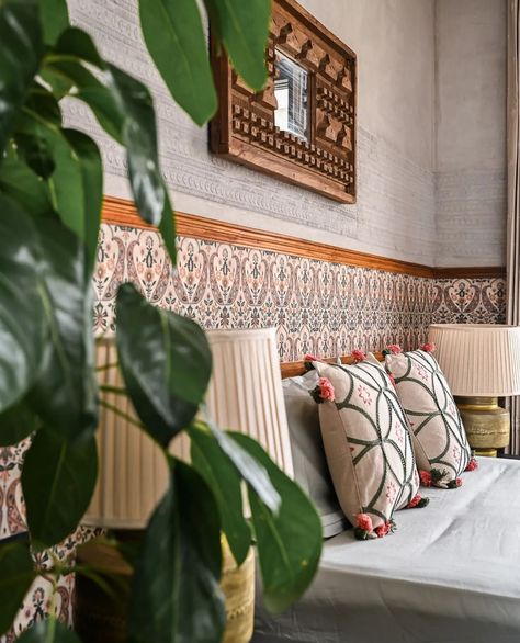 A beautiful guest bedroom space featuring a bespoke antique mirror, Sabyasachi wallpaper accents, brass lamps, and a stunning black slate floor • designed by @studio.Ruh Featuring Sabyasachi ‘Jaipur Valencia’ wallpaper in the color ‘Mogra’ in 2 ways: 1️⃣ Accent Wall Behind Bed: Use the wallpaper on the lower half of the wall for a bold look, paired with a crisp neutral on top for balance. 2️⃣ Art Accent Panel by Desk: Install one roll of wallpaper from ceiling to floor next to the desk f... Indian Themed Bedroom, Sabyasachi Wallpaper, Accent Wall Behind Bed, Wallpaper Accents, Airbnb Photos, Black Slate Floor, Styling Bedroom, Wall Behind Bed, Slate Floor