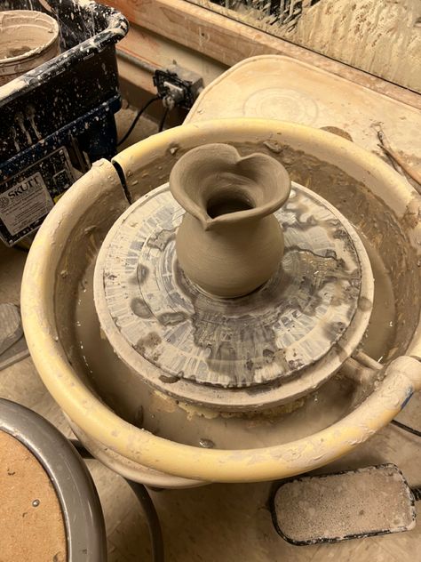 an unfired heart shaped vase made from clay sitting on a potter’s wheel. Pottery Aesthetic Black Woman, Wheel Thrown Pottery Forms, Potter Aesthetic Clay, Ceramic Art Wheel, Ceramic Vase Wheel Thrown, Pottery Asthetic Ideas, Pottery Throwing Aesthetic, Ceramics Class Aesthetic, Wheel Projects Pottery