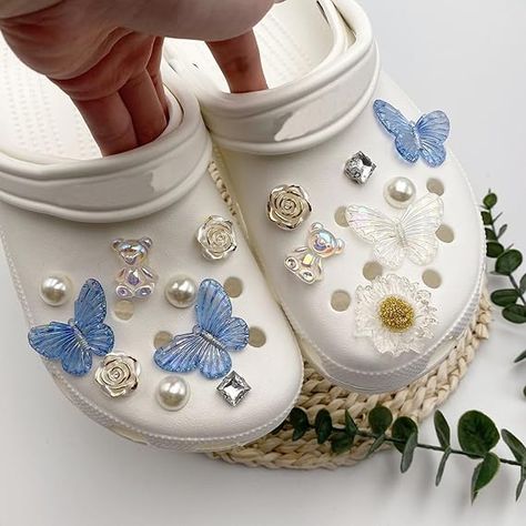 white crocs, blue croc accessories, white pearls, white roses, flower croc accessories, croc charms, croc studs, white butterflies, Y2K fashion, cool crocs, pretty crocs Butterfly Croc Charms, Croc Sandals With Charms, Shoes Butterflies, Cool Crocs, Charms For Shoes, Crocs With Charms, Pearl Shoe, Charms Crocs, Croc Accessories