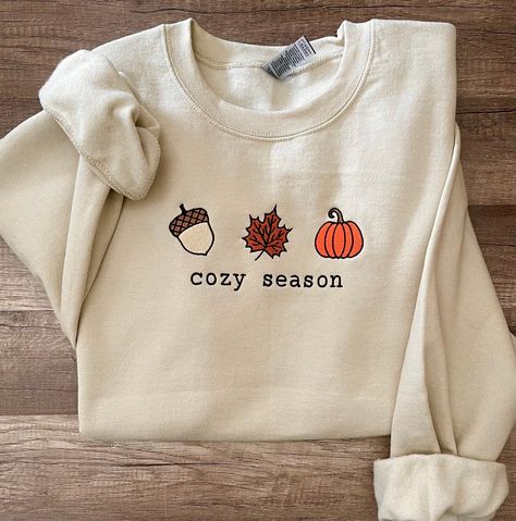 Embroidered COZY SEASON  sweatshirt. *cozy season wording available in thread colors : black, white and orange !  -Material is 50%cotton and 50%polyester. -This is unisex fitting sweatshirt:Size chart is listed in images!  -FYI:I do rotate sweatshirt brands based on size and availability in stock. Measurements,quality and fitting is equal to one another! -Size up for "oversize" look! **Shirt is made to order, and processing times is estimated 5-7  business days!  *Due to nature of Handmade goods this order is not allowed for returns or exchanges, but if you have any concerns, please do contact me and I would be happy to help you! Fall Embroidered Shirts, Fall Sweatshirt Designs, Fall Sweater Designs, Pumpkin Hoodie, Knitted Sweater Design, Fall Graphic Sweatshirt, Diy Fall Sweatshirts, Autumn T-shirt, Cozy Season Sweatshirt