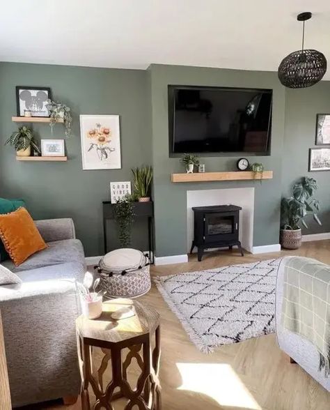 Picture of a cool green living room with a hearth, some shelves, a TV, a grey sofa with pillows, a a rug and some lovely and cool decor Grey Sofa With Pillows, Green Living Room Color Scheme, Living Room Design Green, Sage Living Room, Green Walls Living Room, Sofa With Pillows, Sage Green Living Room, Front Room Decor, Green Living Room Decor