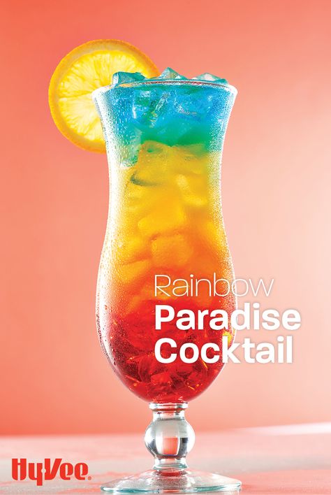 Sip on this layered summer cocktail while daydreaming of your next vacation. This simple rainbow drink recipe is made by slowly pouring in a combination of coconut rum, grenadine, and blue curacao. Cheers to patio happy hours everywhere! Cocktail Recipes Blue Curacao, Paradise Cocktail Recipe, Pride Drink Recipes, Rainbow Mocktails Non Alcoholic, Rainbow Drinks Alcohol, Rainbow Paradise Cocktail, Rainbow Cocktail Recipe, Pride Cocktail Recipes, Drinks With Blue Curacao