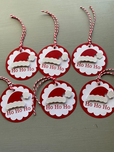 Ho Ho Ho! Get a jump on your Christmas wrapping needs. This listing is for a set of 6 Santa Hat Gift Tags.  These adorable tags are the perfect item to dress up any Holiday Package, Christmas gift or gift basket.  Also great for scrapbooking. Ho Ho Ho is stamped in red ink on a white scalloped circle. Santa's hat is die cut from red card stock and popped to give it dimension.  The hat brim and tassel are die cut from sparkly white glitter paper. The base of the tag is red and die cut from qualit Stamping Up Christmas Gift Tags, Christmas Sticker Gift Tags, Diy Gift Tags Christmas Simple, Family Gift Tags, Christmas Paper Embellishments, Handmade Christmas Tags Ideas, Stampin Up Gift Tags Christmas, Stampin Up Christmas Tags 2024, Scrapbook Tags Ideas