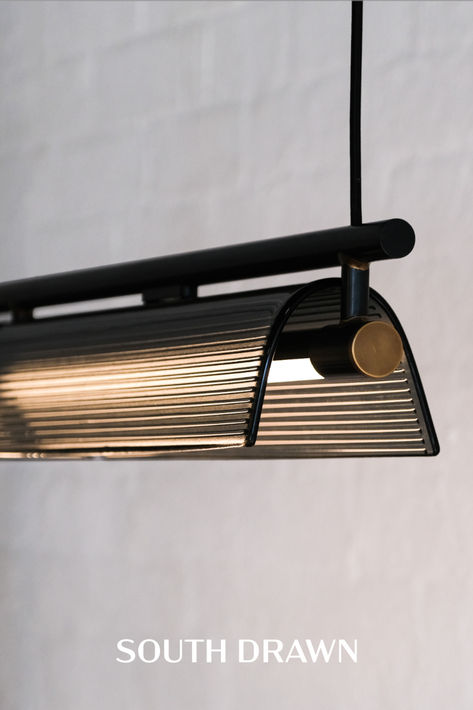 Linear light with grey ribbed glass shades hung from a beautifully resolved black frame Pendant Light Australia, Linear Pendant Lights, Horizontal Pendant Light, Ribbed Pendant Light, Slanted Ceiling Lights, Raked Ceiling Living Room, Lumens Lighting, Linear Lighting Design, Office Restroom