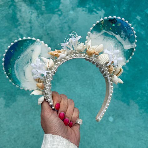 For all my mermaid girlies! These resin ocean wave mouse ears are absolutely stunning. The mouse ears headband is accented with pearls and sea shells, and the waves sparkle with bits of blue. A perfect complement to any mermaid outfit or Ariel inspired look for the parks, these ears are mer-made for you :). Due to the handmade nature of my ears and the artistic quality of resin, each pair will vary slightly, making yours unique and just for you. Just like real ocean waves, no two will be exactly Mermaid Stuff, Moana Gifts, Mini Mouse Ears, Disney Ears Headband, Diy Disney Ears, Disney Themed Outfits, Mermaid Outfit, Mouse Ears Headband, Disney Bound Outfits