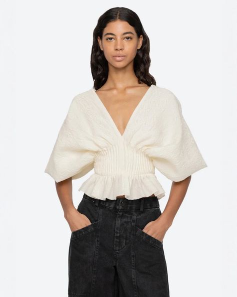 The Elegi Top in Cream by Sea NY is a striking blouse featuring an oversized sleeve, ruffle hem, v-neckline, and pleated bodice. Runs slightly small. If between sizes, size up. self-100% polyester lining-100% cotton Invisible side zip #AW24-014 Jacquard Top, Sea Ny, Pleated Bodice, Kids Sleepwear, Fit Style, Thom Browne, Modern Fashion, Short Sleeve Top, Jeans Dress