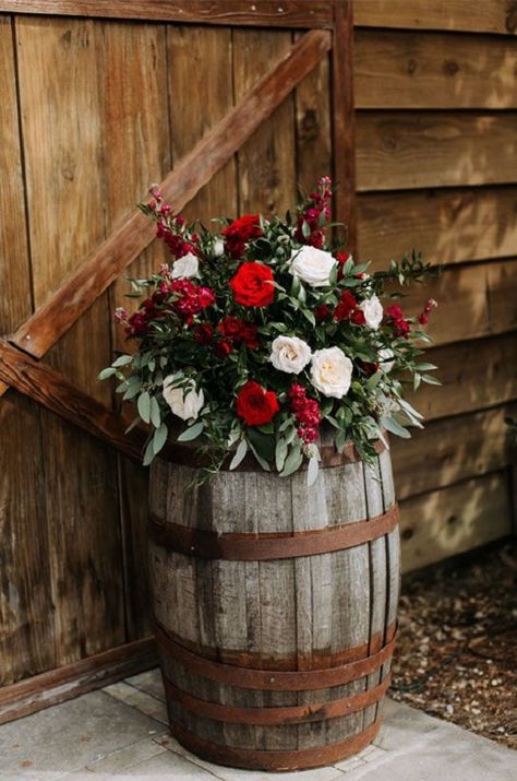 Dark Red, Greenery and Black February Wedding Color Palettes 2024, Dark Red Bridesmaid Dresses, Black Groom Suit - ColorsBridesmaid Floral Arrangement On Wine Barrel, Christmas Wedding Arbor Ideas, Christmas Wedding Rustic, Christmas Country Wedding Ideas, December Wedding Decorations Wedding Table Decor, Christmas Rustic Wedding, Country Christmas Wedding Ideas, Christmas Wedding In Florida, Rustic Red Wedding Decor