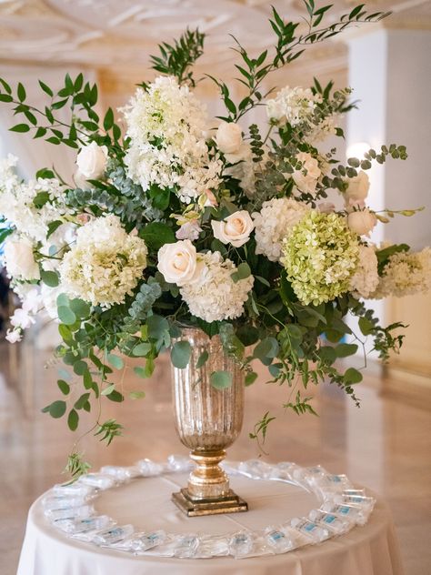 Large centerpiece made with pops of whimsical greenery such Eucalyptus and Italian Ruscus. The flower colors went with the neutral hues used in the Bride's bouquets with soft touches of blush. Big Floral Arrangements Wedding, White Wedding Arrangements Centerpieces, Wedding Flower Arrangements Centerpiece Head Tables, Tall Vase Bouquet, Neutral Flower Arrangements Centerpieces, Tall Flower Arrangements For Table, Tuscan Wedding Flower Arrangements, Green And White Flower Arrangements Tall Centerpiece, Flower Bouquet For Table