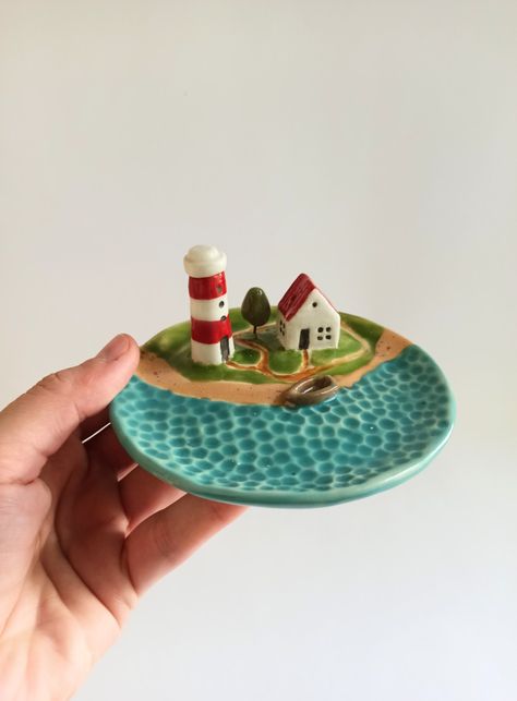 This is a small ceramic dish with a cute lighthouse and house. This is a universal dish for storing jewelry, and it is also a holder for incense sticks. Pottery Small Business, Home Clay Projects, Small Ceramic Dish, Clay Art Jewelry Holder, Ceramics Easy Ideas, Fun Ceramics Ideas, Creative Ceramic Projects, Air Dry Trinket Dish, Clay Jewelry Holders