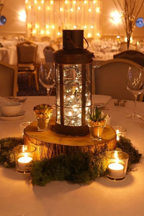 a lantern on a wood block with fairy lights inside and candles surrounding it Cheap Wedding Table Centerpieces, Wedding Candles Table, Lantern Centerpiece, Winter Wedding Centerpieces, Lantern Centerpiece Wedding, Romantic Rustic Wedding, Wedding Renewal, Lantern Ideas, Lantern Centerpieces