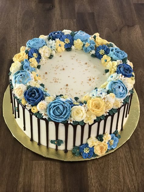 Floral Buttercream Cake. 2 x 10 inch layers using chocolate sponges. Chocolate custard filling. Buttercream coating with a dark chocolate drip. Various shades of dark blue, light blue, yellow and cream flowers. Finished off with white and gold sugar crystals and pearls. 10 Inch Cake Designs, Blue And Yellow Cake Ideas, Blue And Yellow Graduation Cake, Blue Floral Cake Birthday, Yellow And Blue Cupcakes, Blue And Yellow Birthday Cake, Dark Blue Cake, Blue And Yellow Cake, Wedding Cake Designs Blue